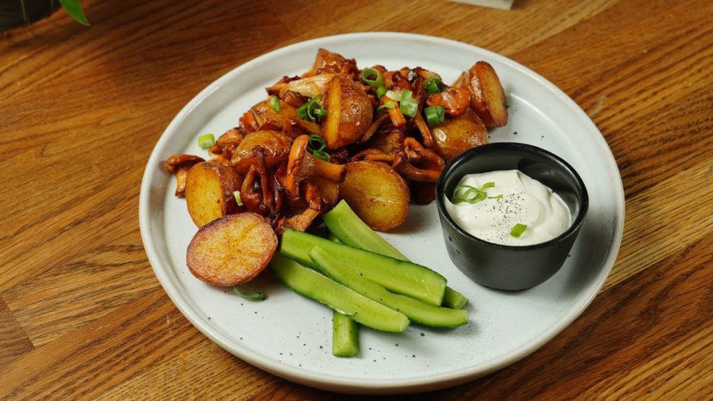 A delectable plate of roast potatoes served with chanterelle mushrooms and fresh cucumbers.